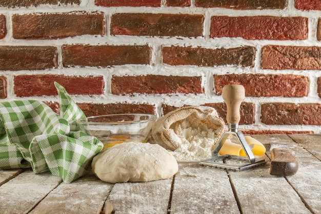 Superficie de madera con masa, mantel y harina