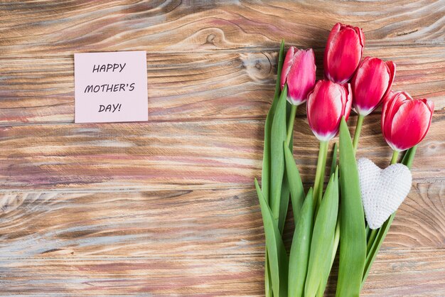 Superficie de madera con nota decorativa y tulipanes para el día de la madre
