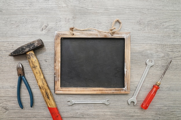 Foto gratuita superficie de madera con pizarra para mensajes y herramientas decorativas