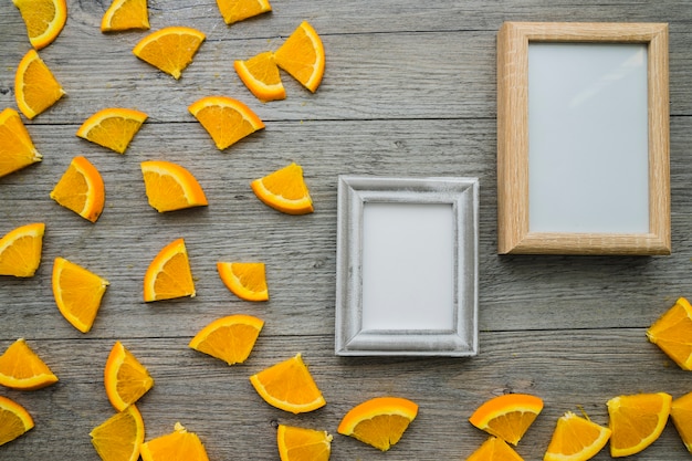 Foto gratuita superficie de madera con trozos de naranja y marcos