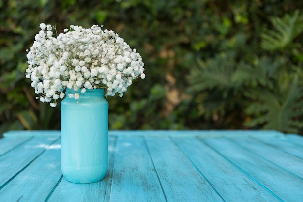 Superficie de tablones azules con flores en un jarrón