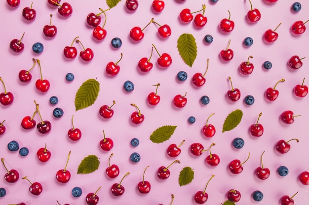 Superficie veraniega con cerezas, arándanos y hojas verdes