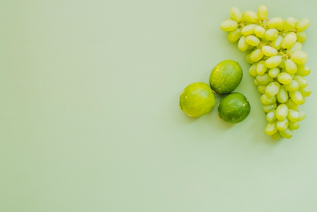 Superficie verde con racimo de uvas y limas