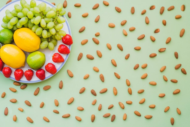 Foto gratuita superficie verde con variedad de frutas sabrosas y almendras