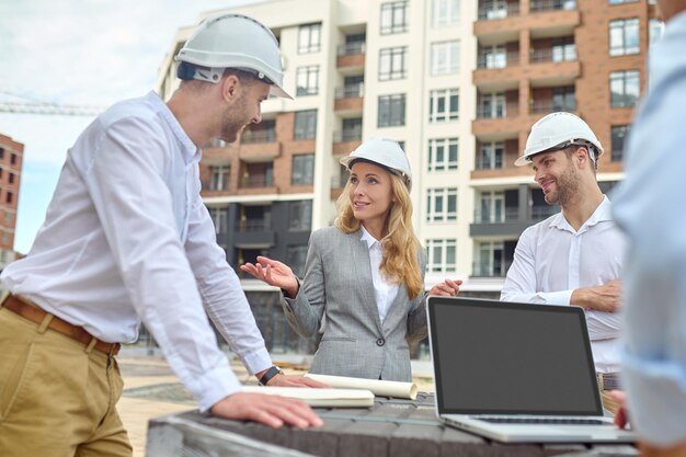 Supervisor de edificio elegante hablando con constructores afuera