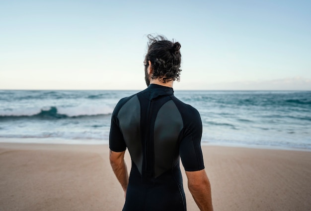 Foto gratuita surfer caminando junto al océano desde detrás de tiro