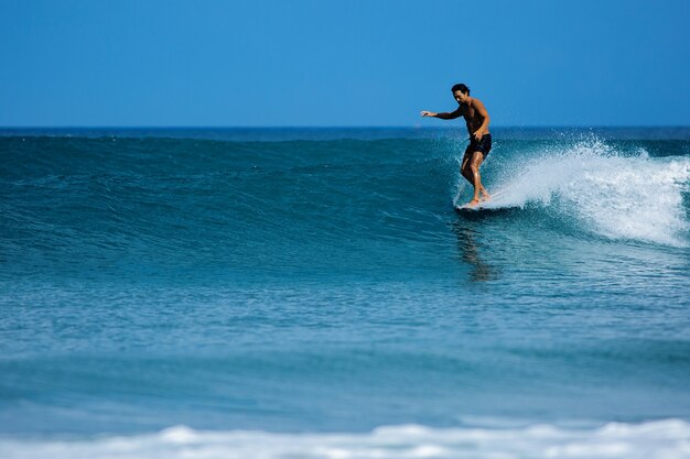 Surfer coreano monta un longboard sobre olas azules