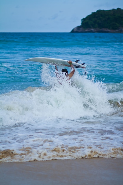 Surfer que lleva la tabla hawaiana en la playa