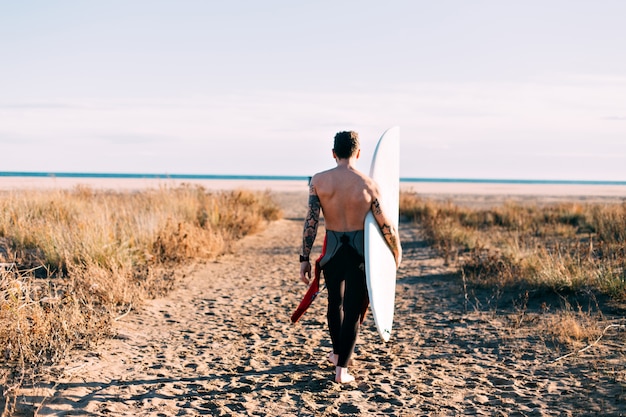 Surfista de moda hipster en la playa con tabla de surf