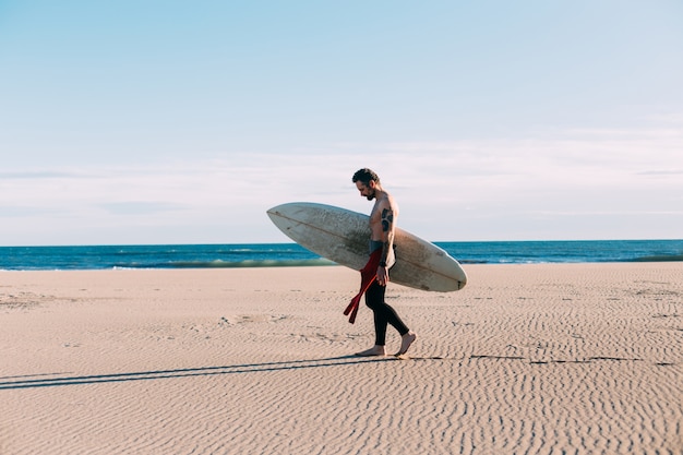 Foto gratuita surfista de moda hipster en la playa con tabla de surf