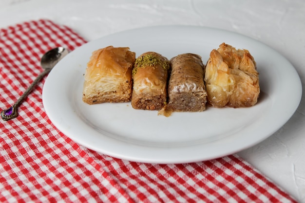 Surtido de baklava turco con cuchara y trapo en plato redondo