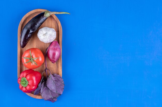 Surtido colorido de verduras frescas maduras sobre tabla de madera.