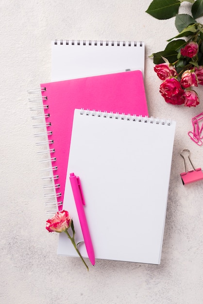 Surtido en cuadernos con bolígrafo y ramo de rosas.