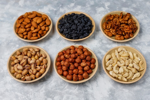 Surtido de frutos secos en platos de cerámica. Anacardo, avellanas, nueces, pistacho, nueces, piñones, maní, pasas vista superior.