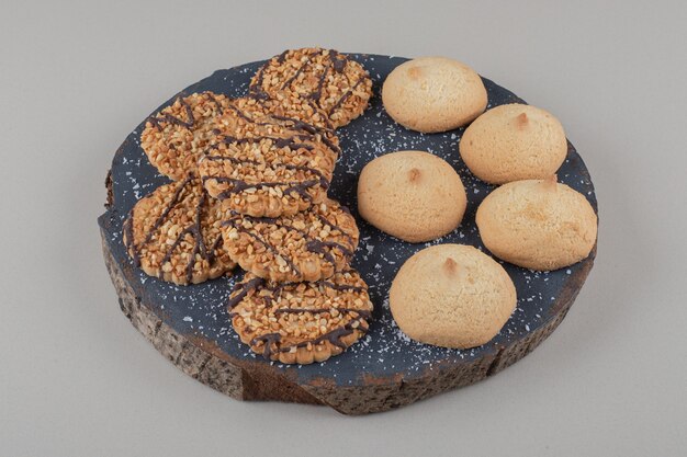 Surtido de galletas apiladas sobre una tabla de madera sobre fondo de mármol.