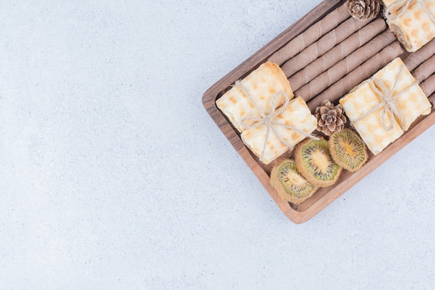 Surtido de galletas y kiwi seco sobre tabla de madera.