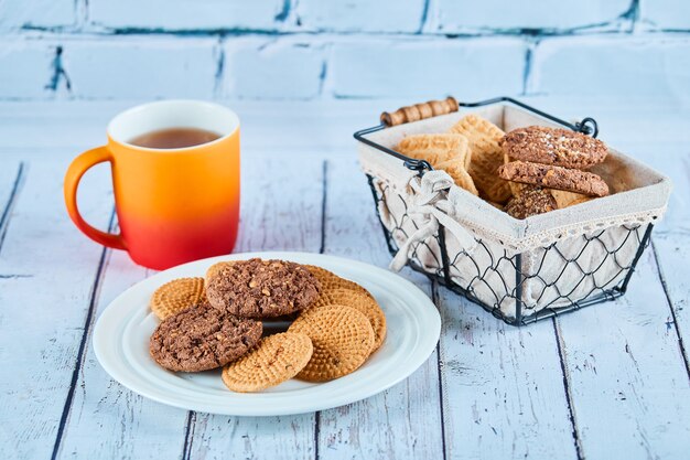 Surtido de galletas en plato y canasta y una taza en el cuadro azul.