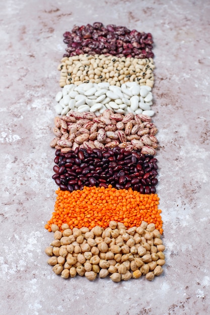 Surtido de legumbres y frijoles en diferentes tazones sobre fondo de piedra clara. Vista superior. Comida sana de proteínas veganas.