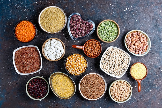 Surtido de legumbres y frijoles en diferentes tazones sobre fondo de piedra clara. Vista superior. Comida vegana saludable de proteínas.