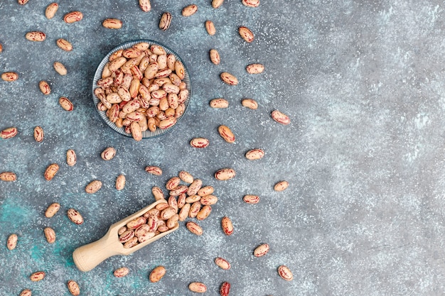 Surtido de legumbres y frijoles en diferentes tazones sobre superficie de piedra clara. Vista superior. Comida sana de proteínas veganas.