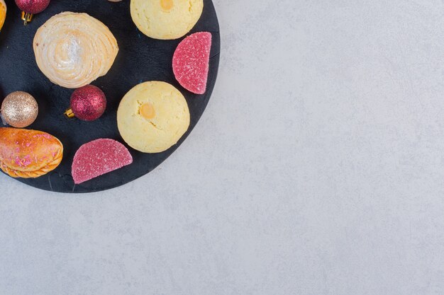 Surtido de mermeladas y galletas festivas en pizarra.