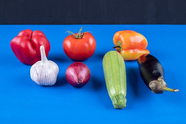 Surtido de muchas verduras frescas maduras en superficie azul