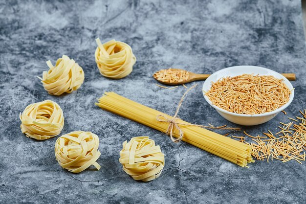 Surtido de pasta cruda con cuchara de madera.