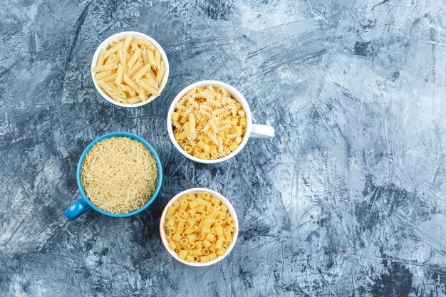 Surtido de pasta en tazones de fuente vista superior sobre un fondo de yeso gris