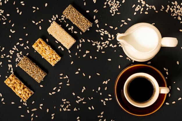 Surtido plano de barras de cereales con leche y café sobre fondo liso