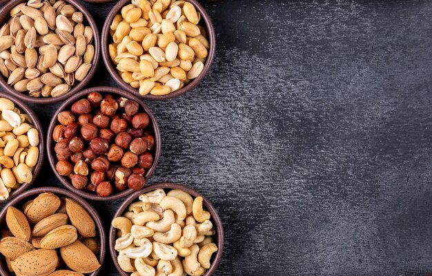 Surtido plano de frutos secos y frutas secas en mini tazones diferentes con nueces, pistachos, almendras, maní