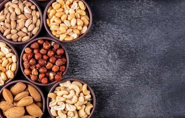 Surtido plano de frutos secos y frutas secas en mini tazones diferentes con nueces, pistachos, almendras, maní