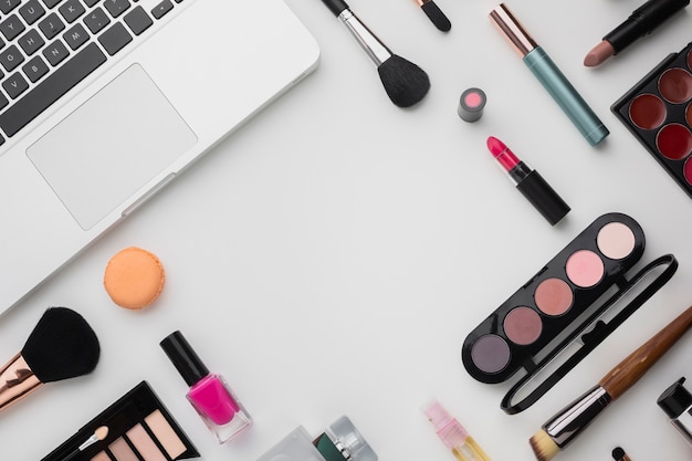 Surtido plano con paletas de maquillaje y laptop