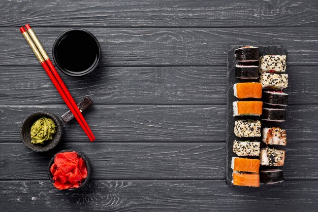 Surtido plano de sushi maki en pizarra con palillos
