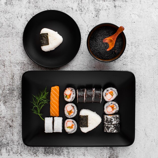 Surtido plano de sushi en plato rectangular negro con espacio de copia