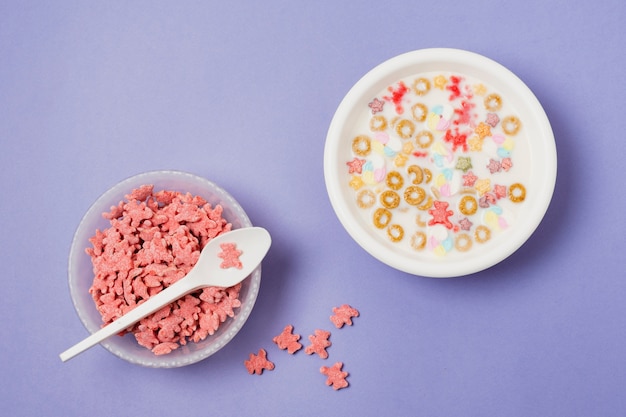 Surtido plano con tazón de cereal sobre fondo morado