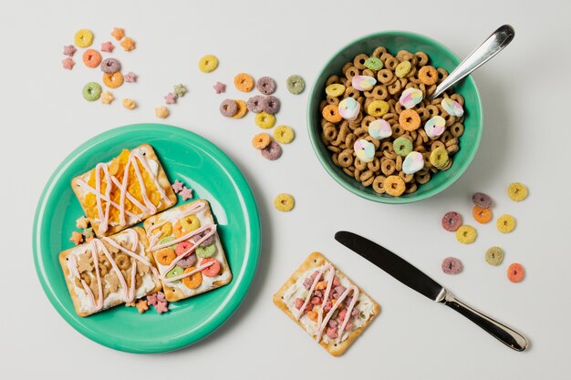 Surtido plano con tazón de cereal y tartas en un plato