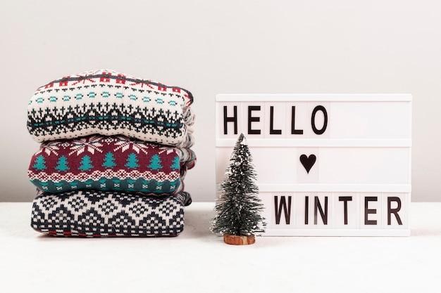 Surtido con suéteres y hola cartel de invierno