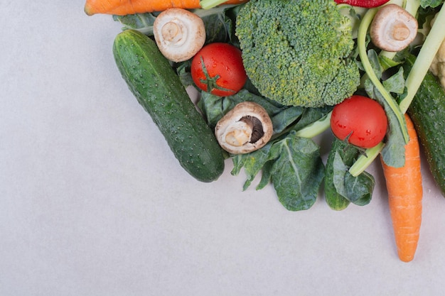 Surtido de verduras crudas sobre superficie blanca.