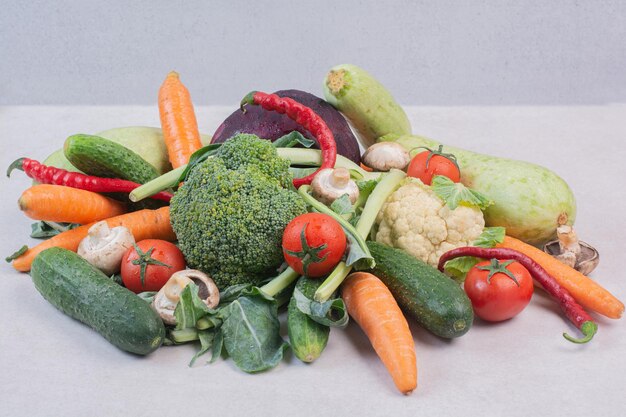 Surtido de verduras frescas sobre superficie blanca.