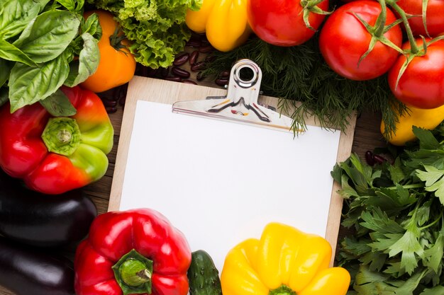 Surtido de verduras laico plano con portapapeles vacío