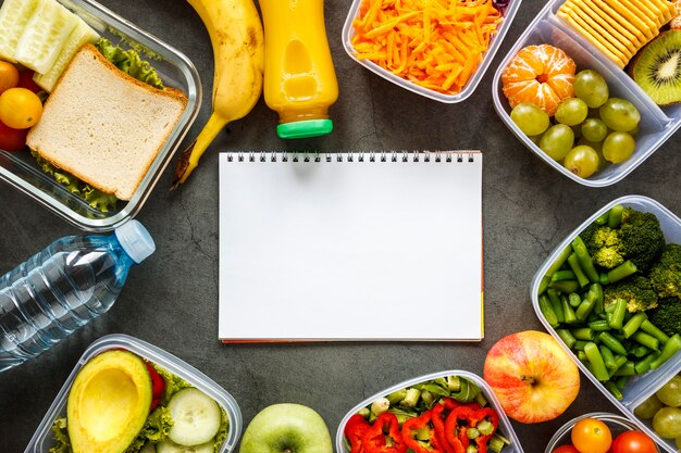 Surtido de vista superior de alimentos por lotes cocinados con un cuaderno vacío