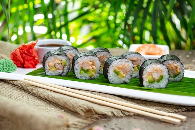 Sushi al horno con wasabi, jengibre y salsa de soja sobre una hoja de bambú