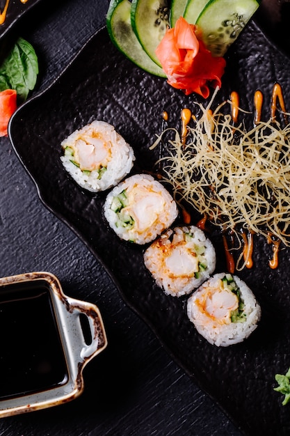 Sushi nori con salsa de soja dentro de un plato negro.