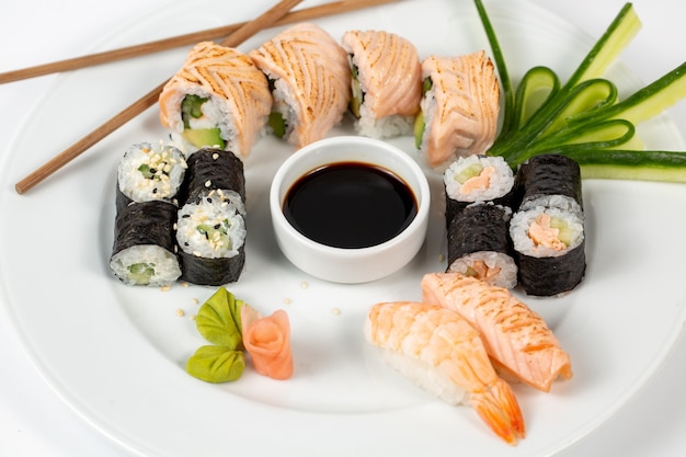 Sushi con salsa de soja en medio de un plato y palillos