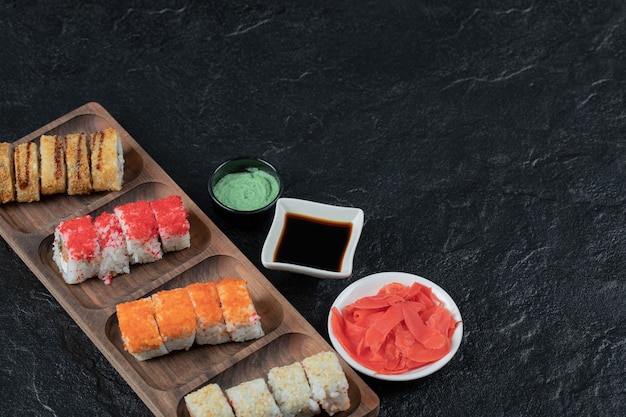 Sushi en una tabla de madera con wasabi, jengibre y salsa de soja.