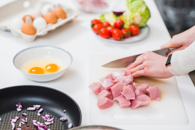 Tabla de cocina con manos cortando carne