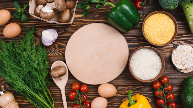 Tabla de cortar circular con verduras frescas en la mesa