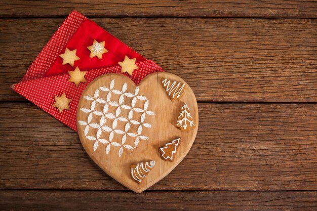 Tabla de cortar con forma de corazón con galletas sobre una servilleta roja