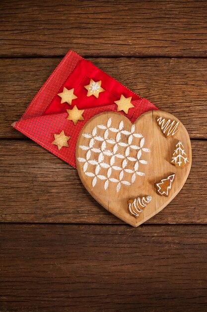 Tabla de cortar con forma de corazón con galletas sobre una servilleta roja