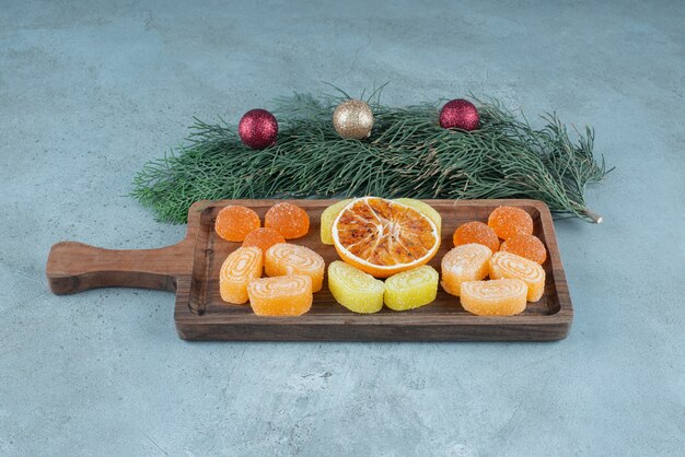 Una tabla de cortar de madera con mermeladas de frutas y naranjas secas.